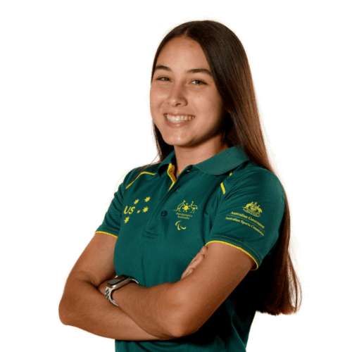 Young woman (Rhiannon Clarke) with brunette hair, wearing a green t-shirt is looking into the camera.