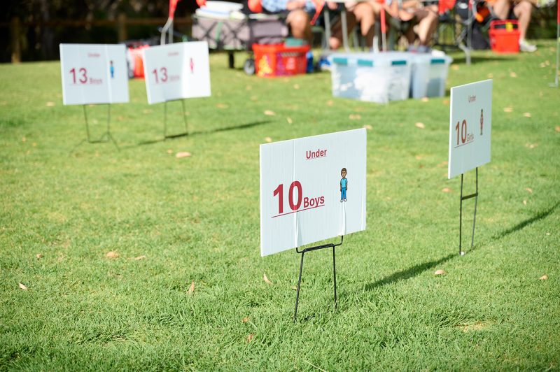 Signs indicating age group categories for a boys' sports event, with one sign for "Under 10 Boys" and others for "13."