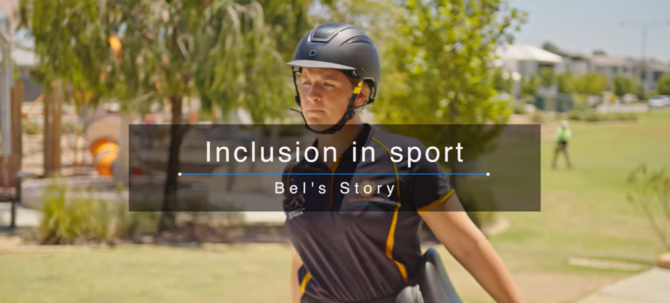 A woman wearing a black riding helmet and a black shirt, walking in a grassy field. There is a text overlay on the image reading “Inclusion in sport - Bel’s story”.
