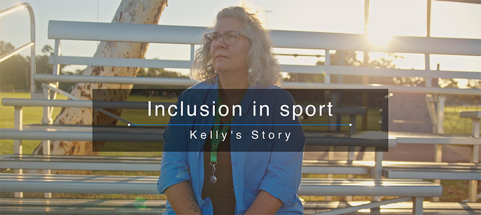 The image features a woman sitting on a bench, looking off into the distance. She appears to be deep in thought or contemplating her surroundings. She is wearing a light blue shirt with a sunflower lanyard around her neck. There is text overlay on the image reading “Inclusion in Sport - Kelly’s Story”.