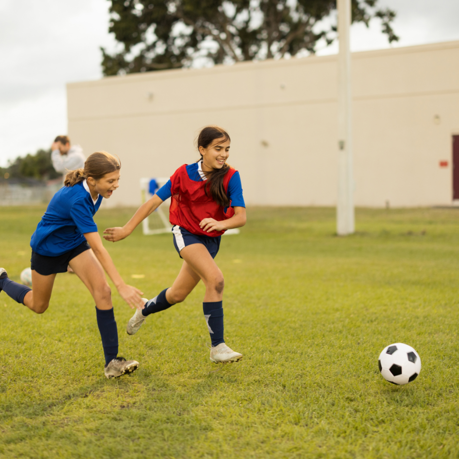 Two girls in sports gear playing football with a text beside image Inclusive Sport Pathways Workshop
